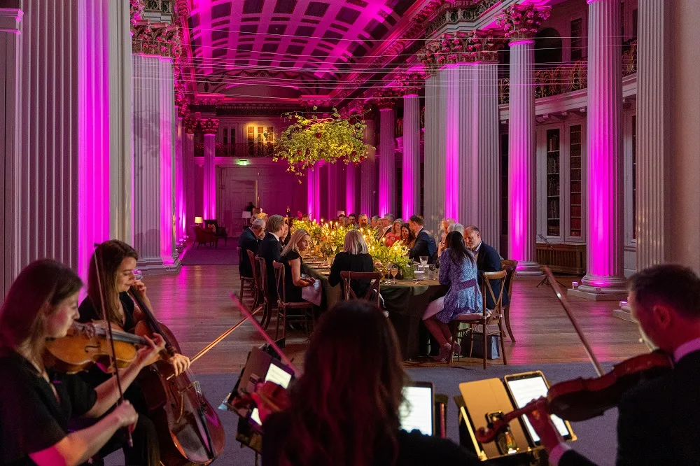 Guests dining beneath pink event lighting