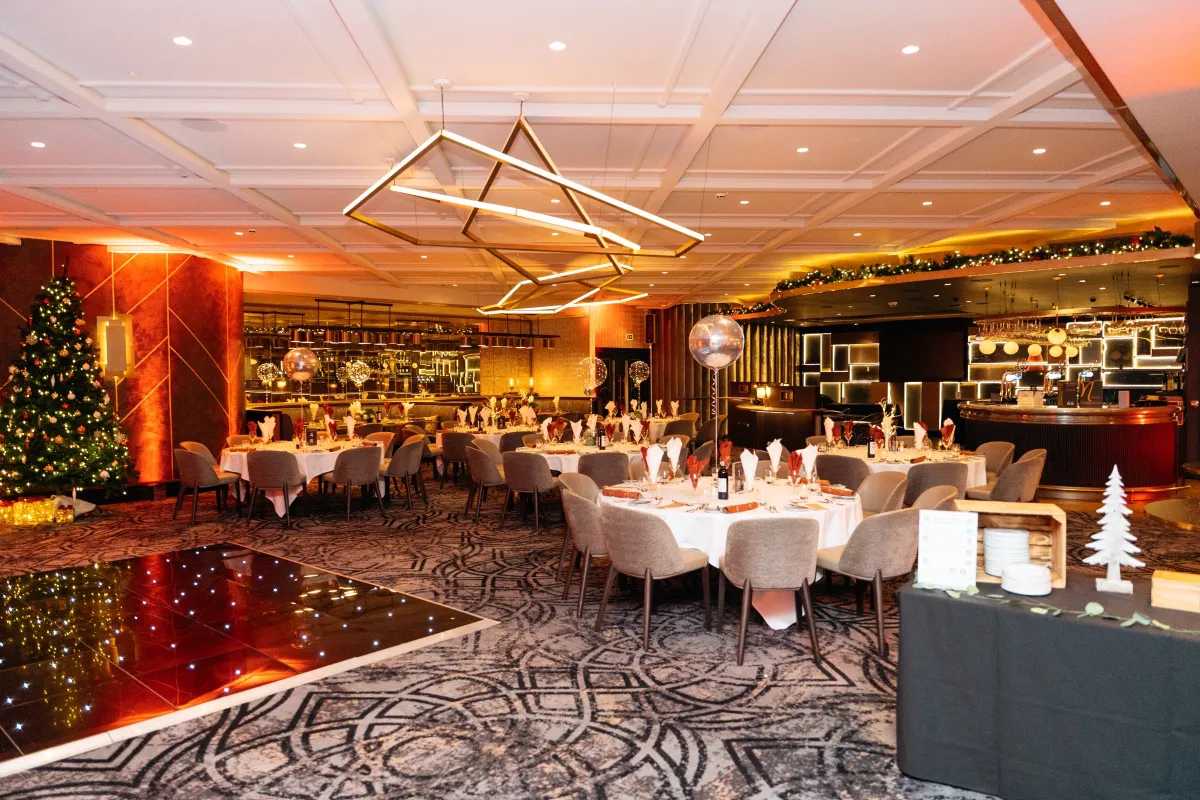 A dining room dressed with Christmas trees and warm lighting
