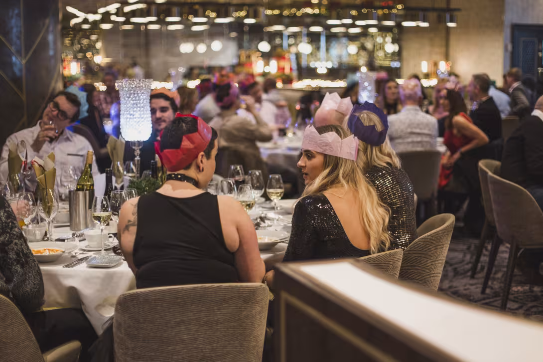 Guests in party hats celebrating at a Christmas dinner