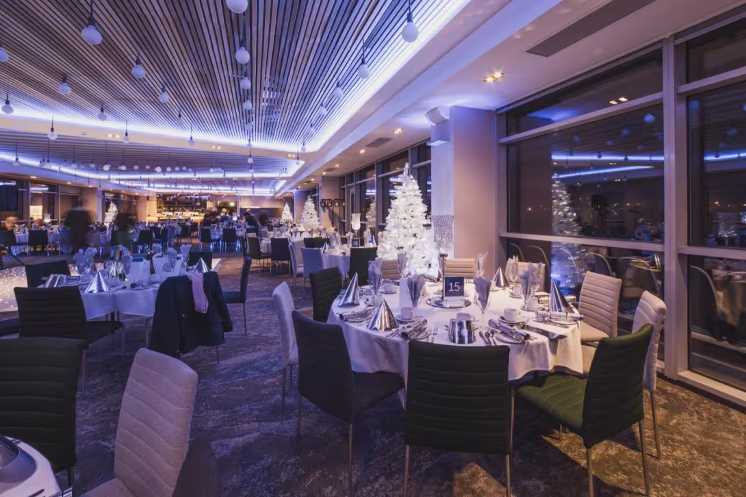 A Christmas party set for dinner beneath white festive trees